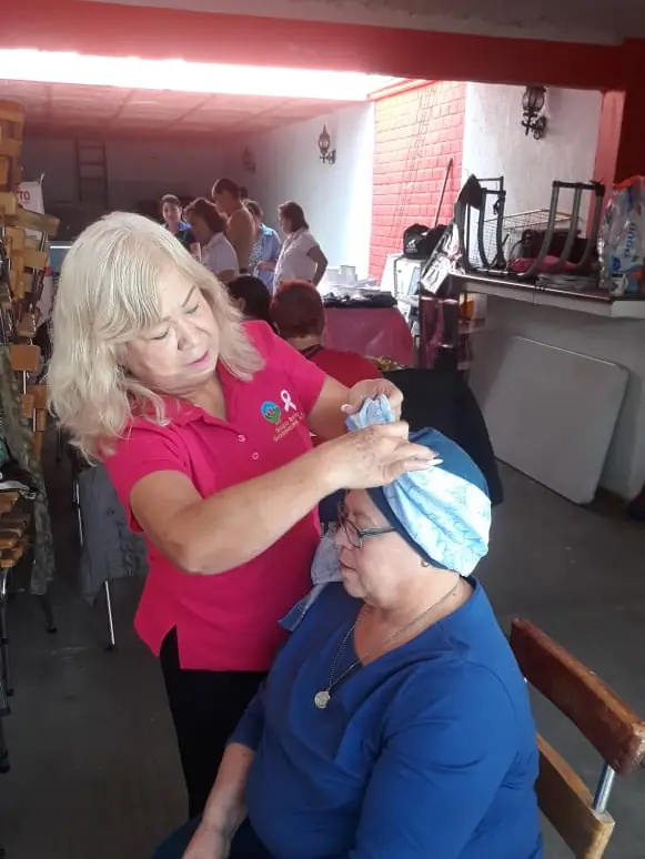 Voluntaria colocando un turbante a una paciente