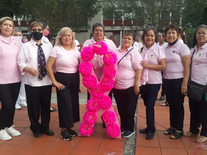 Voluntarias de Grupo RETO Guadalajara con playeras rosas y un listón de flores gigante en la calle